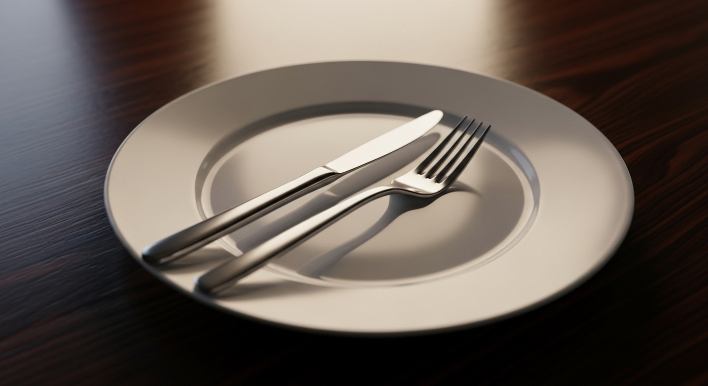 Đĩa sứ trắng với dao nĩa bạc đặt gọn gàng ở vị trí đã dùng xong, minh họa quy tắc lịch sự trên bàn ăn.